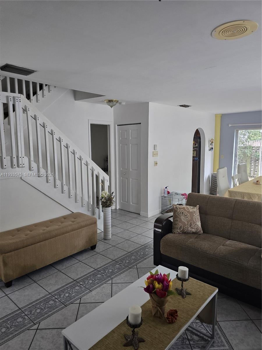 A living room features a white staircase, tiled floors, a brown sofa, and a coffee table — 12687 SW 146th St, Miami FL 33186, MIAMI, FL