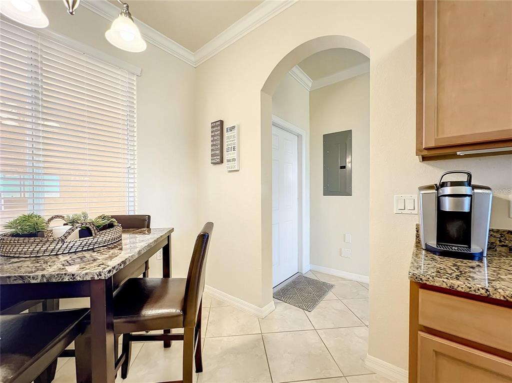 A dining area with a granite-topped table, tile flooring, and an arched doorway — 8205 GRAND ESTUARY TRAIL UNIT 403, BRADENTON, FL