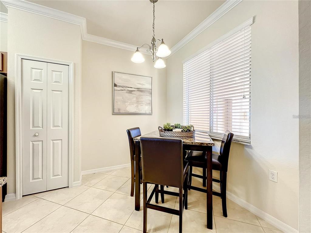 A dining area features a dark table with four chairs, a chandelier, and tile flooring — 8205 GRAND ESTUARY TRAIL UNIT 403, BRADENTON, FL