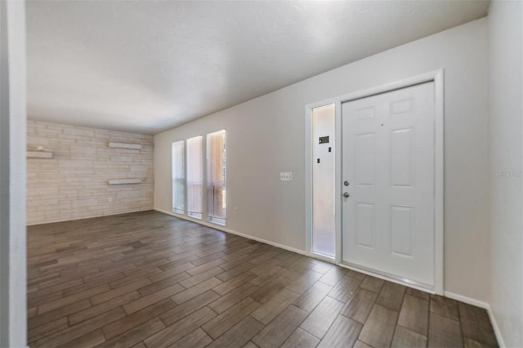 An entryway with wood-look tile flooring, a white front door, and a stone accent wall — 1124 DANNY DRIVE, SARASOTA, FL