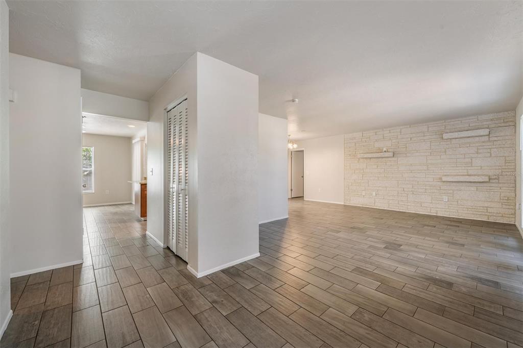 An interior view shows a living room with a stone accent wall and wood-look tile flooring — 1124 DANNY DRIVE, SARASOTA, FL