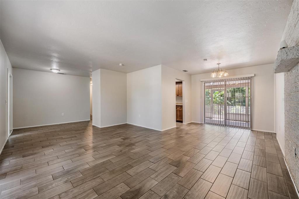 An open living area with wood-look tile flooring, a stone fireplace, and sliding glass doors — 1124 DANNY DRIVE, SARASOTA, FL
