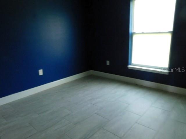 An empty room features dark blue walls, light gray tile flooring, and a single window — 3724 TRACY STREET, FORT MYERS, FL