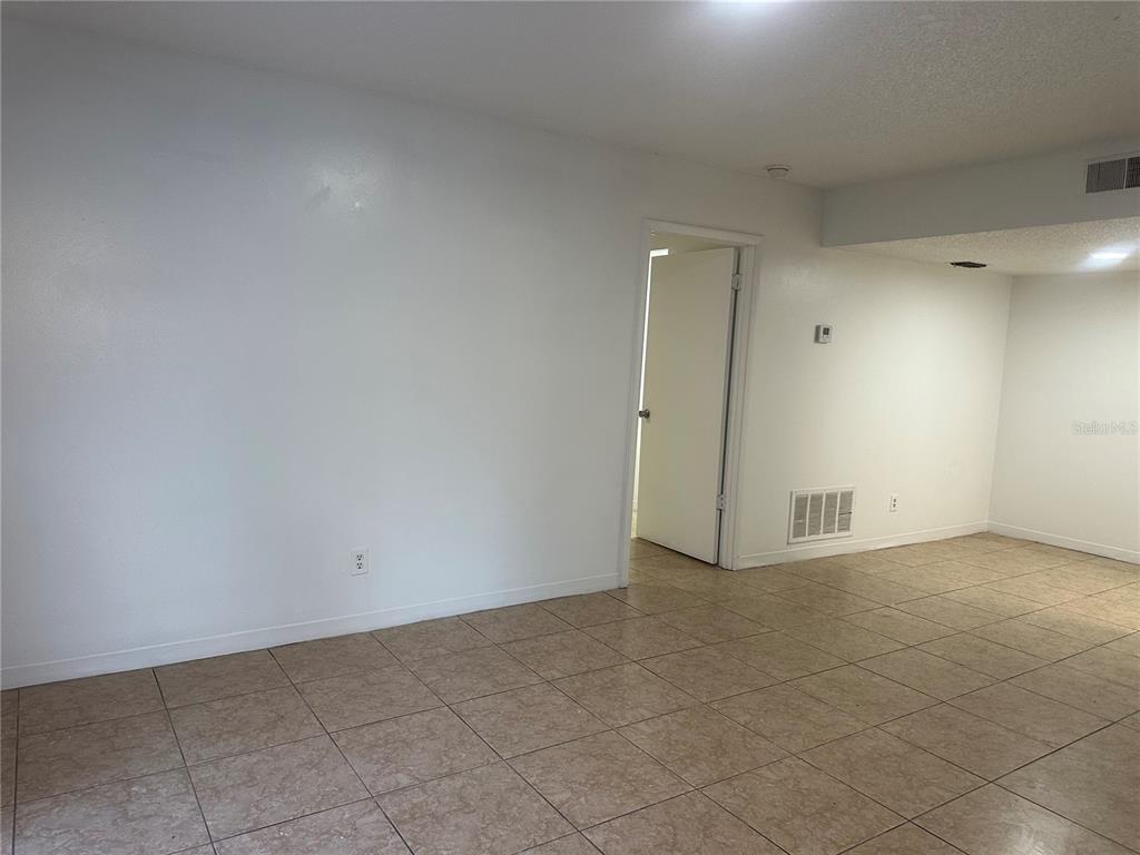 An empty room features beige tile flooring, white walls, and a doorway leading elsewhere — 8426 CAMDEN STREET UNIT A, TAMPA, FL