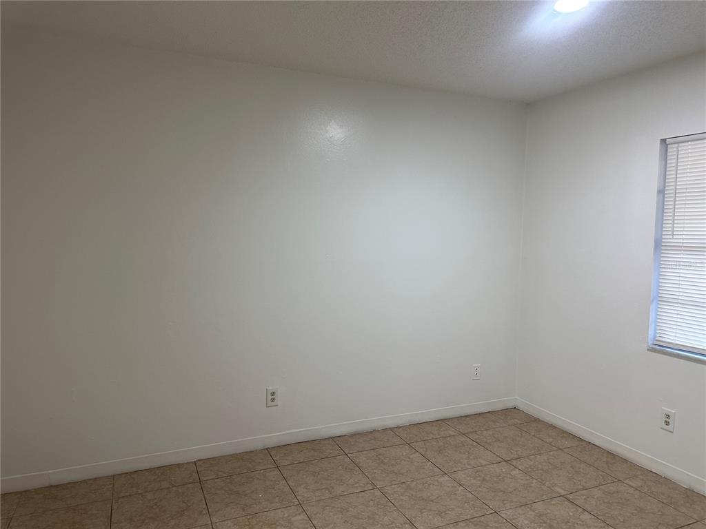 An empty room features white walls, tile flooring, and a window with blinds — 8426 CAMDEN STREET UNIT A, TAMPA, FL