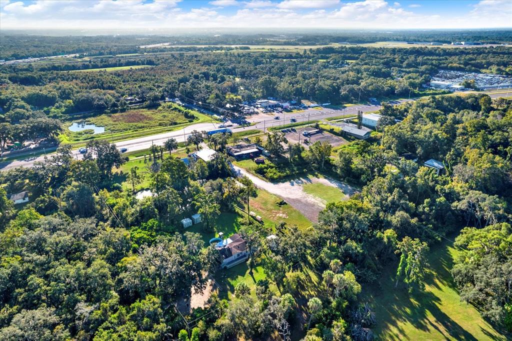 An aerial view shows a house with a pool surrounded by trees and a road — 9211 HARNEY BAPTIST CHURCH ROAD, TAMPA, FL