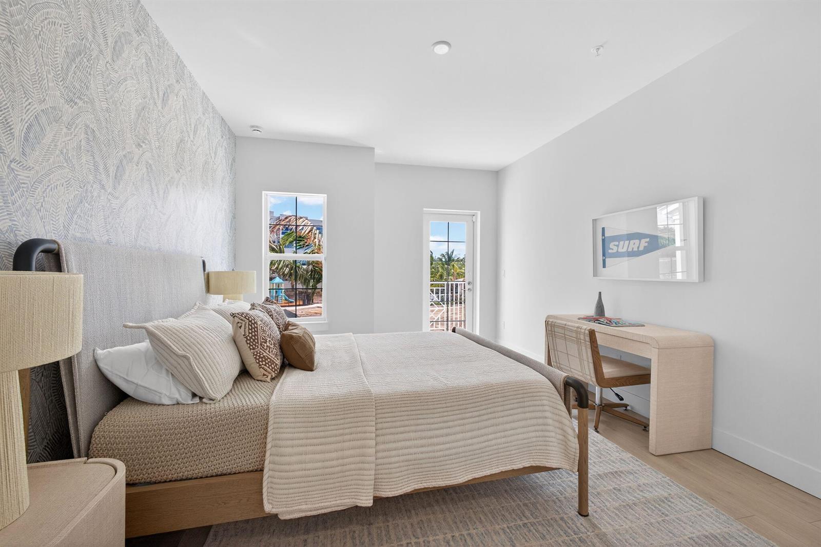 A bedroom features a patterned accent wall, a bed, a desk, and a balcony door — 115 Water Pointe Place # 34, Jupiter FL 33477, JUPITER, FL