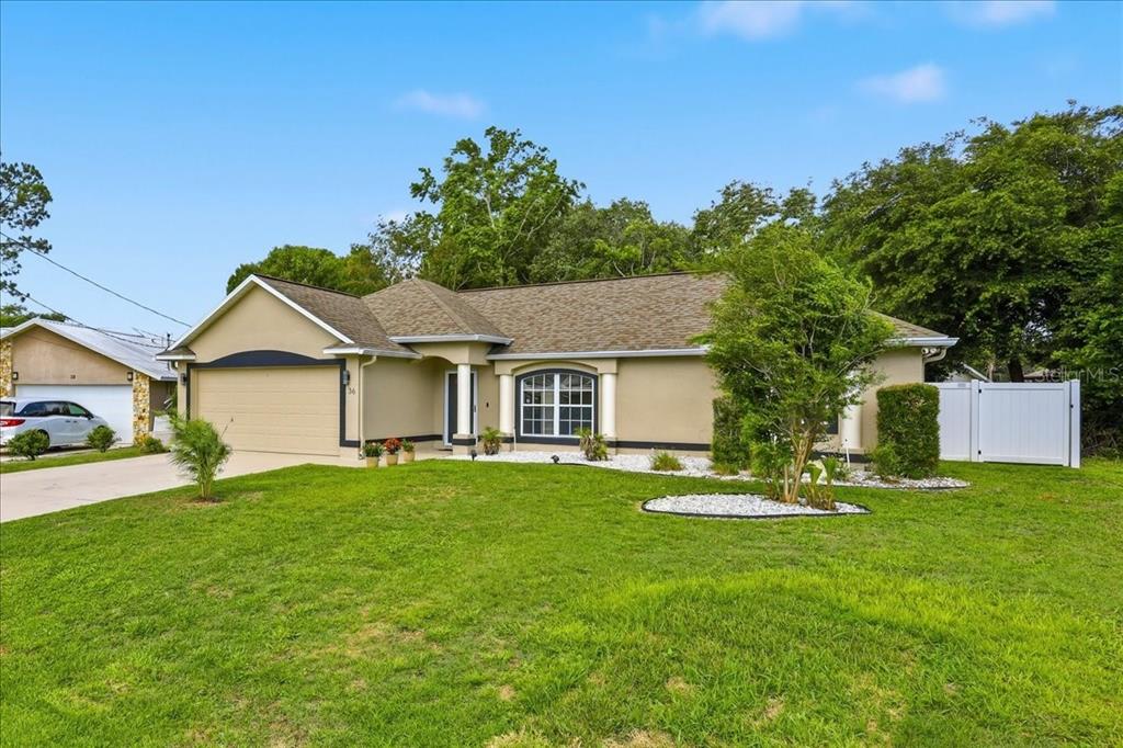 A single-story house with a tan exterior, a two-car garage, and a white privacy fence — 36 FORGE LANE, PALM COAST, FL