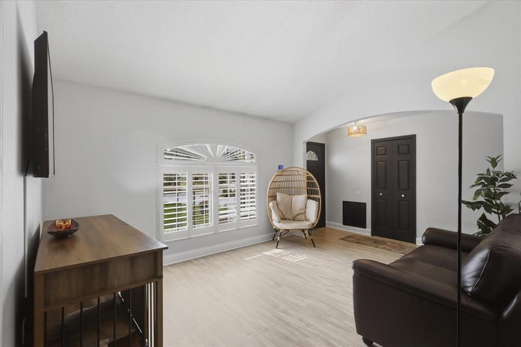 A living room with light wood-look flooring, a hanging wicker chair, and a dark sofa — 36 FORGE LANE, PALM COAST, FL