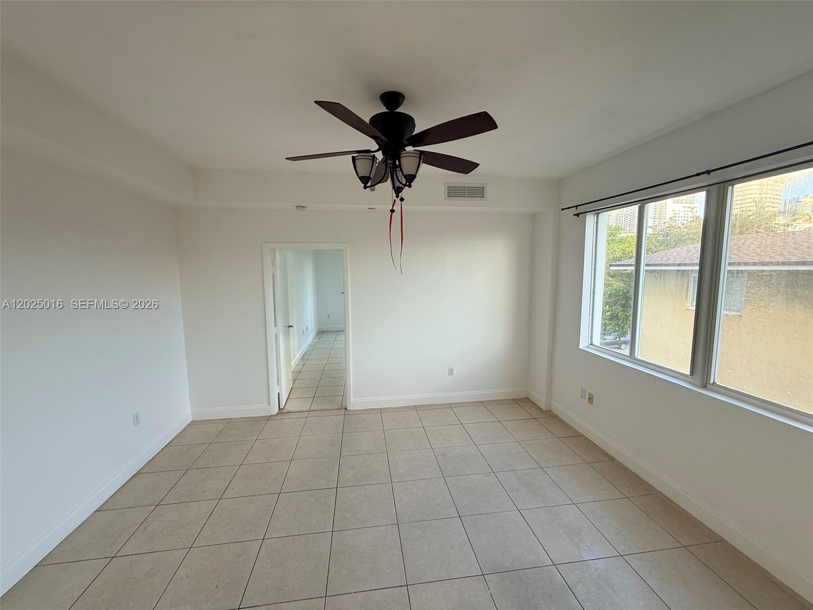 An empty room features white walls, tile flooring, a ceiling fan, and a large window — 400 SW 2nd St # 201, Miami FL 33130, MIAMI, FL
