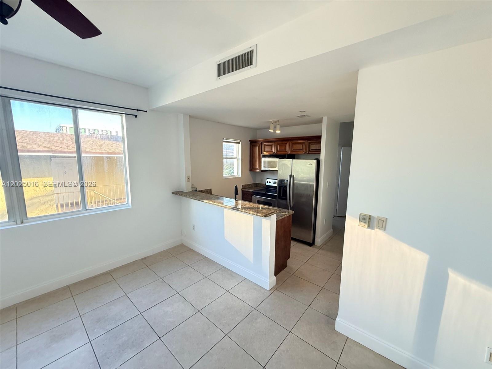 A kitchen with granite countertops and stainless steel appliances opens to a tiled dining area — 400 SW 2nd St # 201, Miami FL 33130, MIAMI, FL