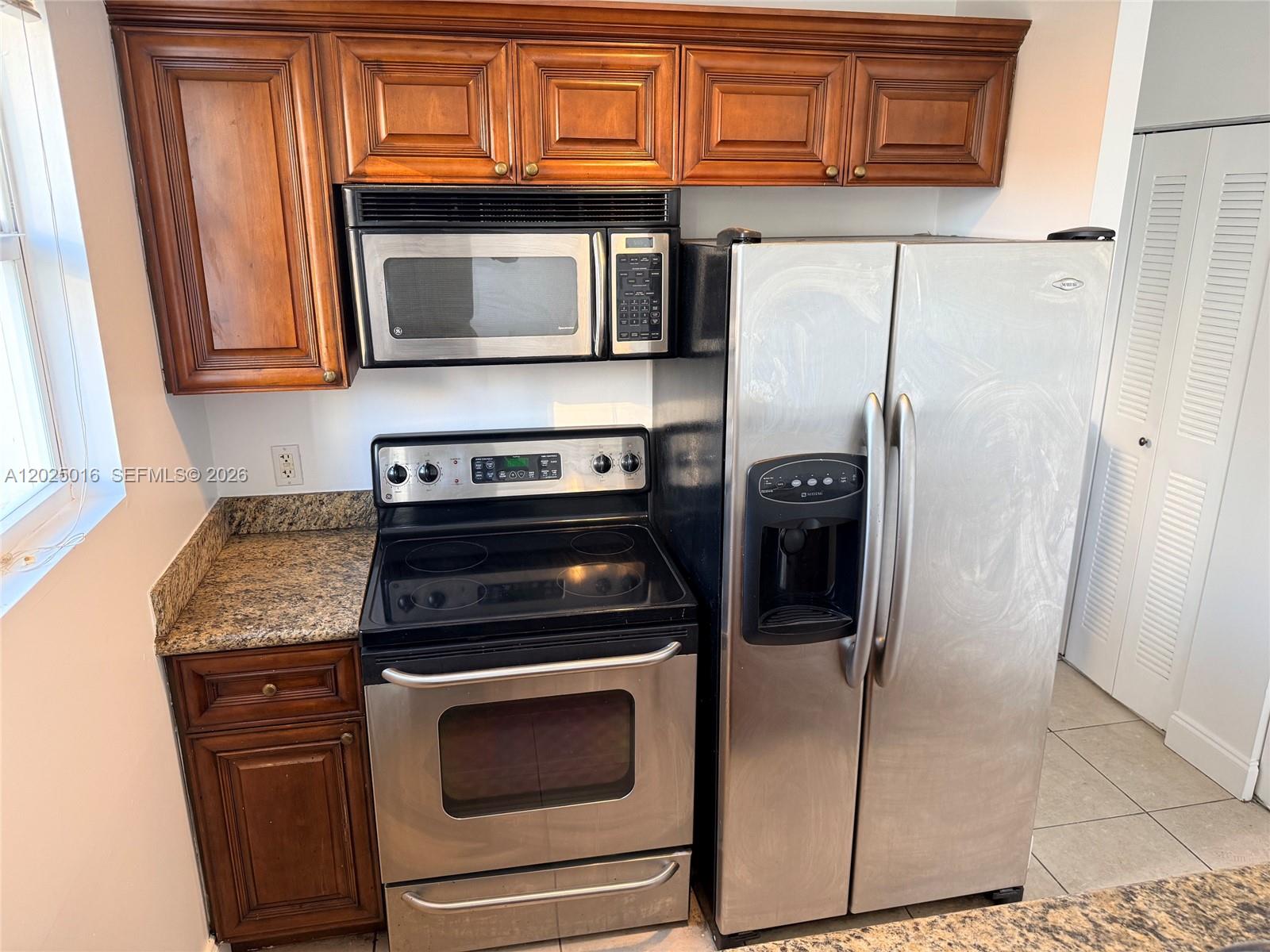 A kitchen features wood cabinets, stainless steel appliances, and granite countertops — 400 SW 2nd St # 201, Miami FL 33130, MIAMI, FL