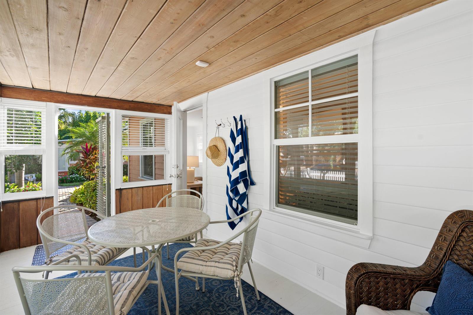 A sunroom features a white shiplap wall, wood-paneled ceiling, dining set, and outdoor views — 118 SE 7th Avenue, Delray Beach FL 33483, DELRAY BEACH, FL