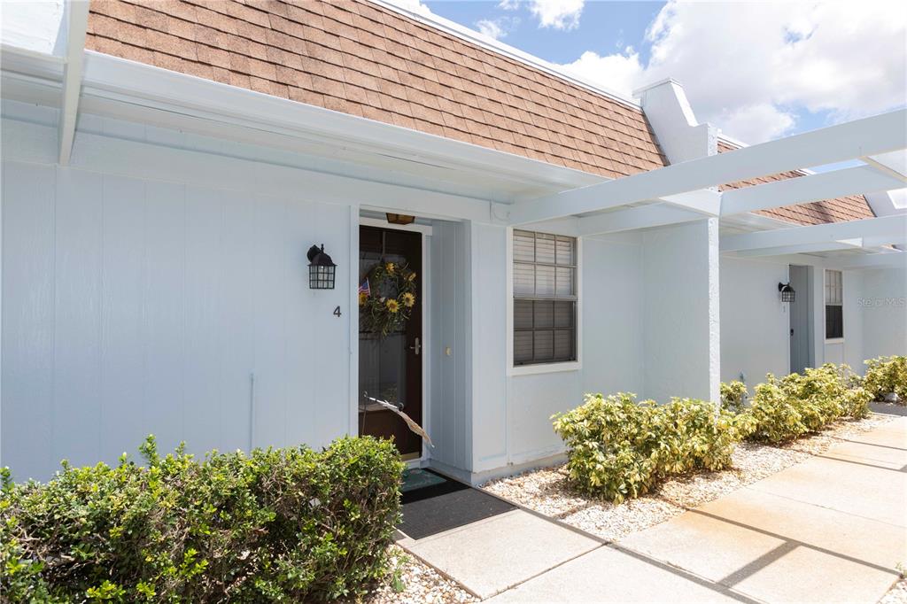 A light blue exterior wall features a front door marked with the number four — 11140 CARRIAGE HILL DRIVE UNIT 4, PORT RICHEY, FL
