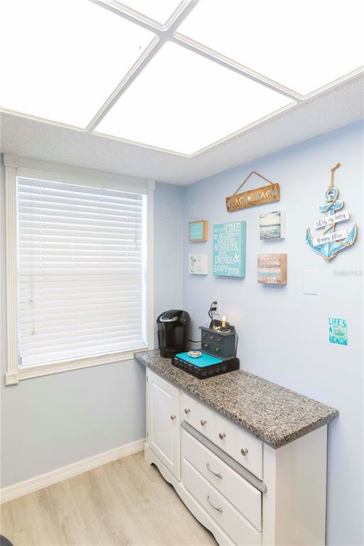 A coffee station with a granite countertop and white cabinets sits against a light blue wall — 11140 CARRIAGE HILL DRIVE UNIT 4, PORT RICHEY, FL