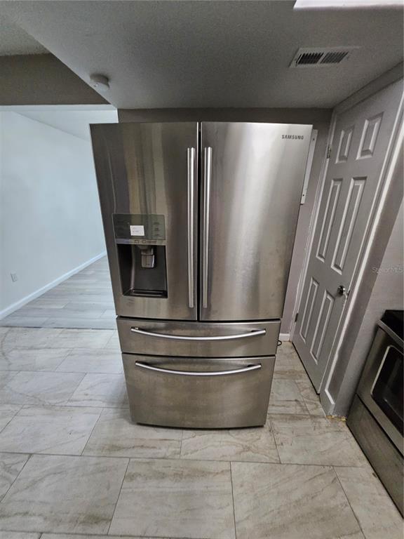 A stainless steel Samsung French door refrigerator stands in a kitchen with light tile flooring — 2787 L B MCLEOD ROAD UNIT 2787A, ORLANDO, FL