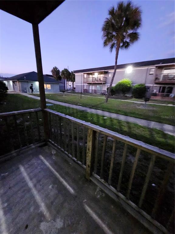 A wooden balcony overlooks a grassy courtyard with apartment buildings and a palm tree — 2787 L B MCLEOD ROAD UNIT 2787A, ORLANDO, FL
