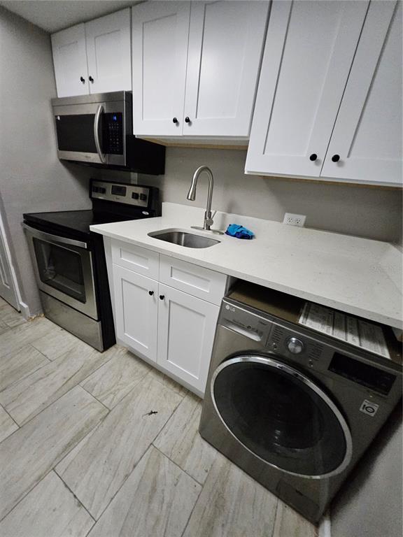 A kitchen features white cabinets, stainless steel appliances, a sink, and a front-loading washing machine — 2787 L B MCLEOD ROAD UNIT 2787A, ORLANDO, FL