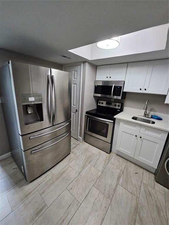 A kitchen features stainless steel appliances, white cabinetry, and light-colored tile flooring — 2787 L B MCLEOD ROAD UNIT 2787A, ORLANDO, FL