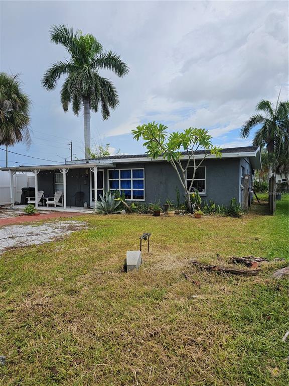 A single-story gray house with a covered porch and palm trees in the front yard — 105 COLONIA LANE W, NOKOMIS, FL