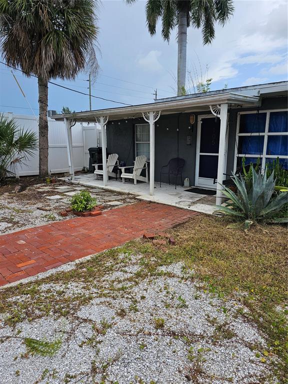 A gray house exterior features a covered front porch, brick walkway, and a palm tree — 105 COLONIA LANE W, NOKOMIS, FL