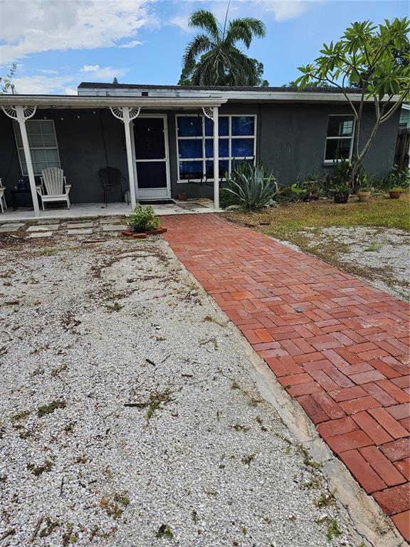 A single-story house with a dark gray exterior, a brick walkway, and a covered porch — 105 COLONIA LANE W, NOKOMIS, FL