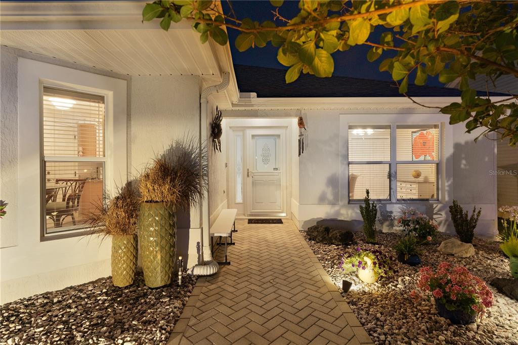 A single-story house with a paved driveway, garage, and landscaped front yard at twilight — 16689 SE 78TH LIVE OAK AVENUE, THE VILLAGES, FL