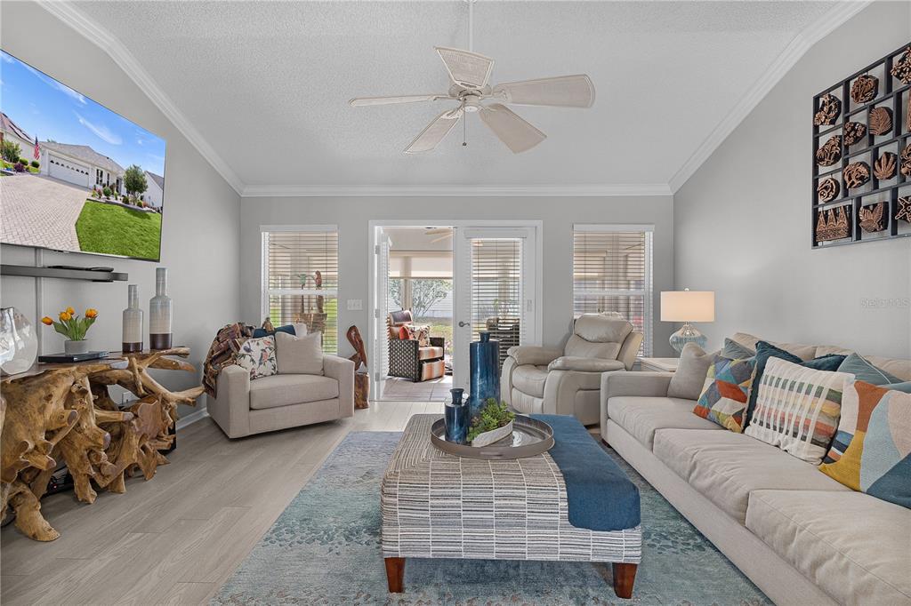 A living room features a light gray sofa, patterned ottoman, area rug, and ceiling fan — 16689 SE 78TH LIVE OAK AVENUE, THE VILLAGES, FL