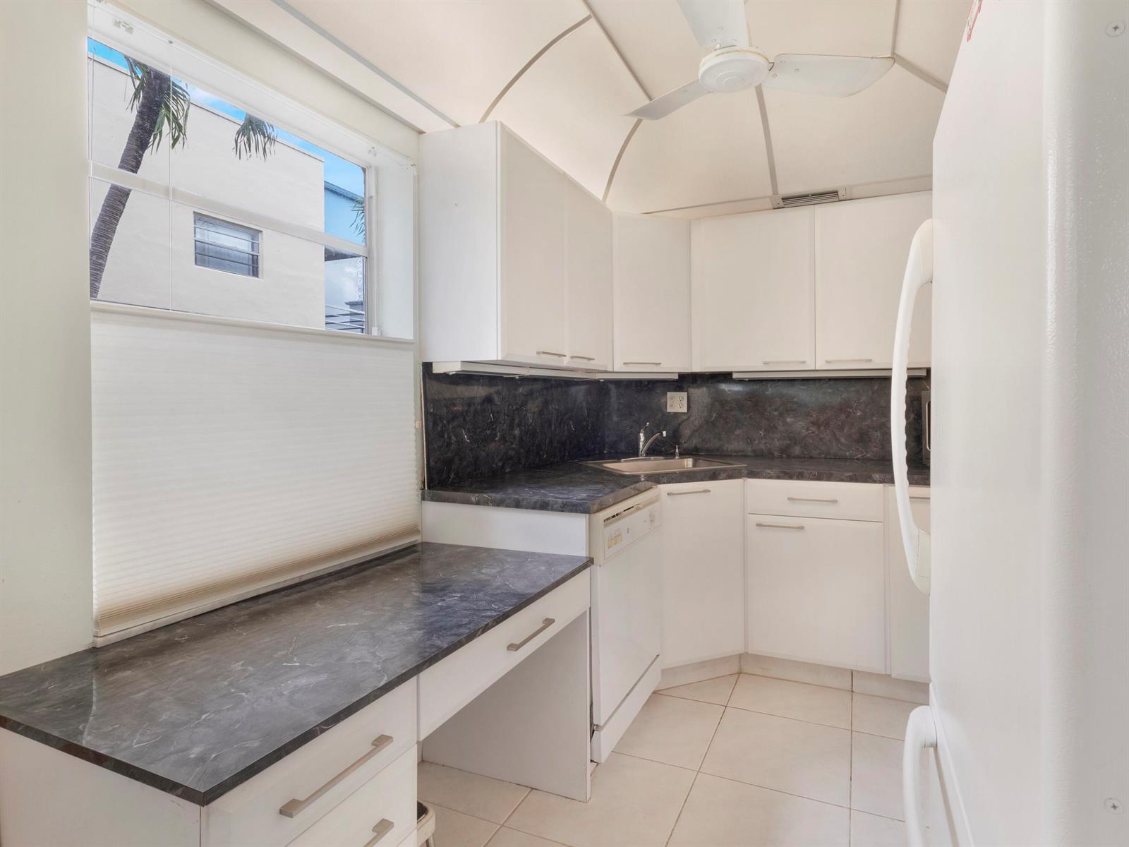 A kitchen with white cabinets, dark marble-look countertops, a dishwasher, and a window view — 405 Burgundy I, Delray Beach FL 33484, DELRAY BEACH, FL