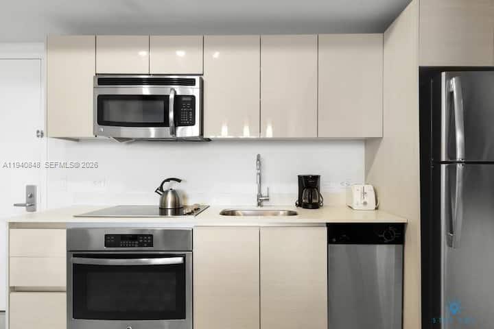 A modern kitchen features stainless steel appliances, light-colored cabinetry, and a white countertop — 2602 E Hallandale Beach Blvd # R2006, Hallandale Beach FL 33009, HALLANDALE BEACH, FL