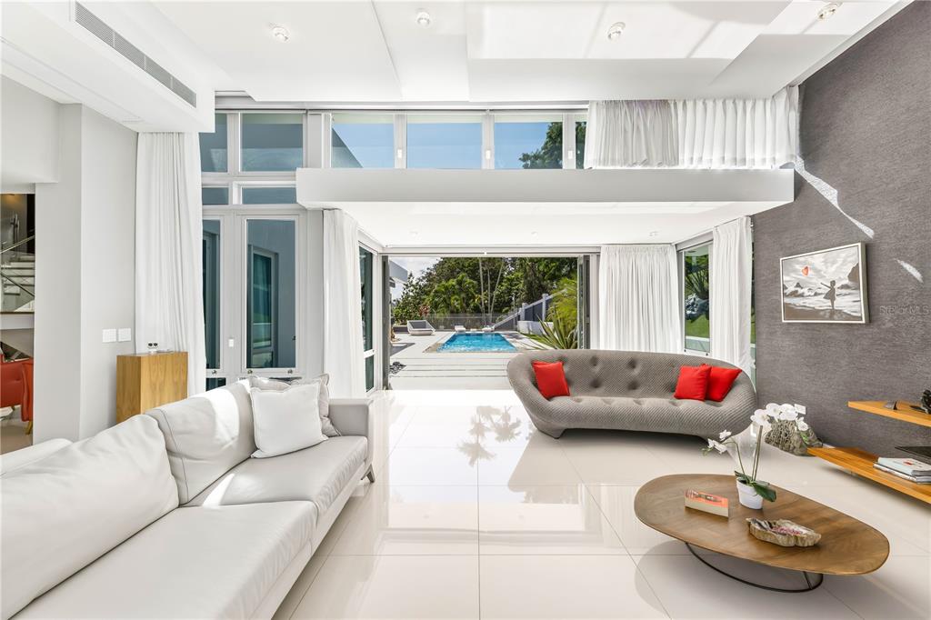 A modern living room with white tile floors opens to a backyard pool and patio — B32 EASTSIDE COURT, GUAYNABO, PR