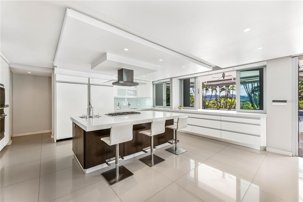 A modern kitchen features a large island with bar seating, white cabinetry, and large windows — B32 EASTSIDE COURT, GUAYNABO, PR