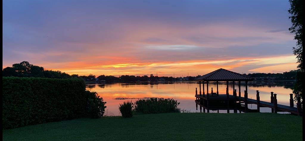 A wooden dock with a covered gazebo extends into a lake at sunset — 3108 TROY DRIVE, ORLANDO, FL