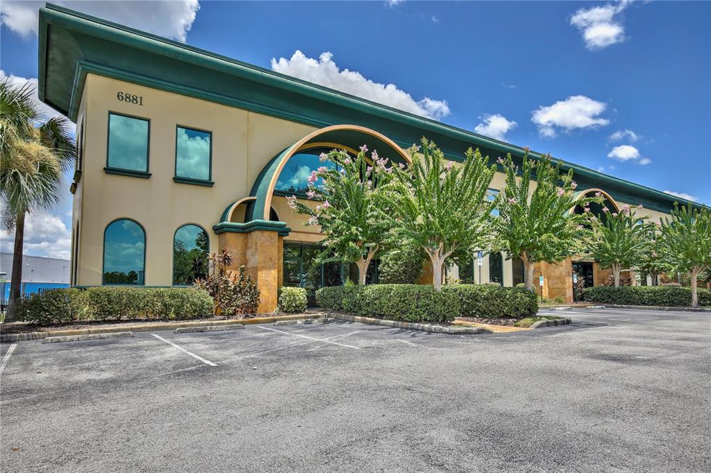 A two-story commercial building with a tan facade, green trim, and a paved parking lot — 6881 KINGSPOINTE PARKWAY UNIT 1&2, ORLANDO, FL