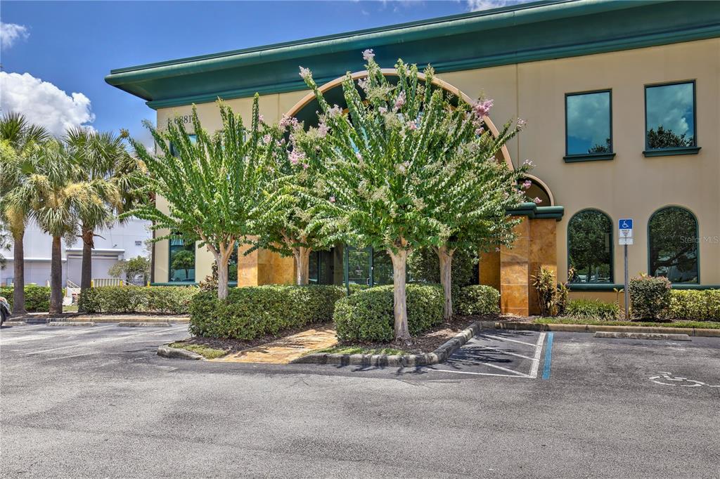 A two-story commercial building features a tan facade, green trim, and a paved parking lot — 6881 KINGSPOINTE PARKWAY UNIT 1&2, ORLANDO, FL