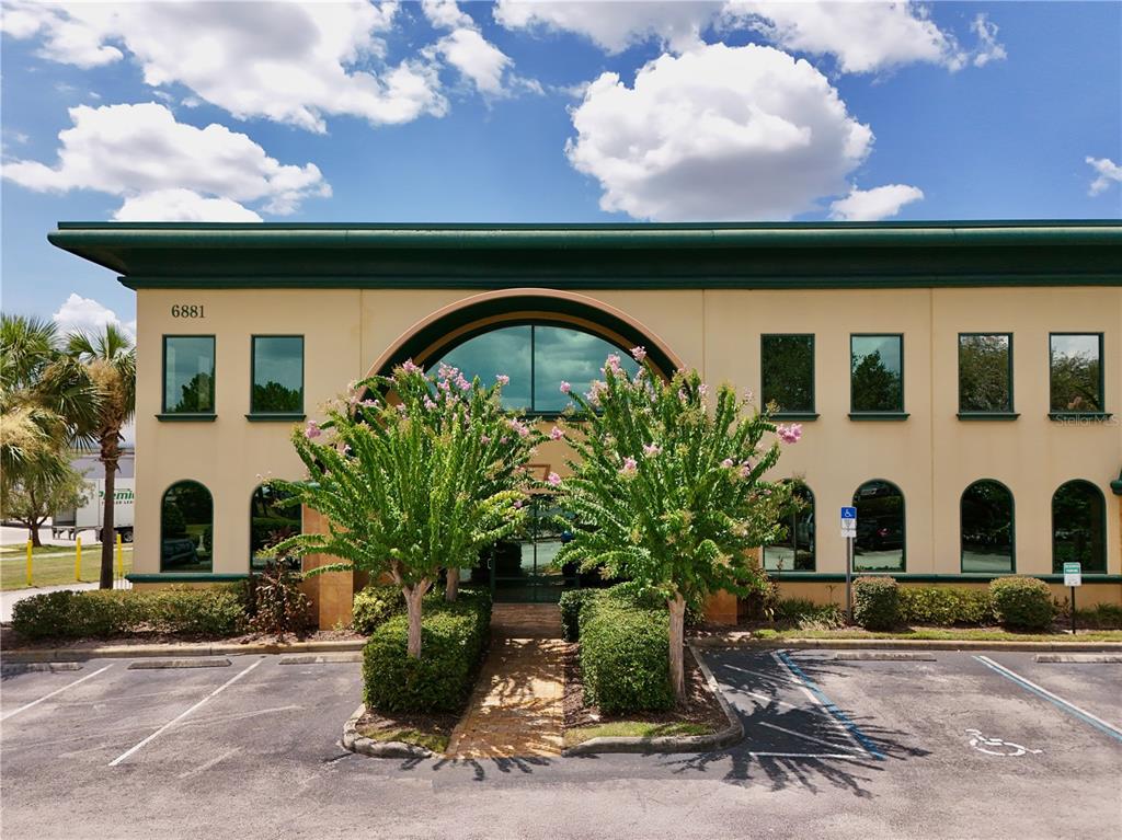 A two-story commercial building features a central arched entrance and a paved parking lot — 6881 KINGSPOINTE PARKWAY UNIT 1&2, ORLANDO, FL