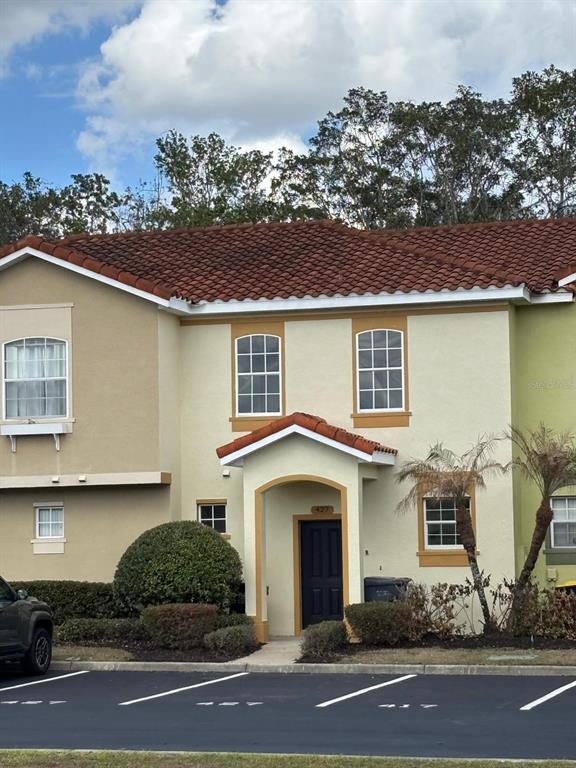 A two-story townhouse exterior features a tan stucco facade, a tiled roof, and a front entrance — 427 MADISON CIRCLE, DAVENPORT, FL
