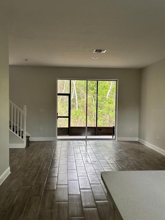 An open living area features wood-look tile flooring, a staircase, and sliding glass doors to a lanai — 427 MADISON CIRCLE, DAVENPORT, FL