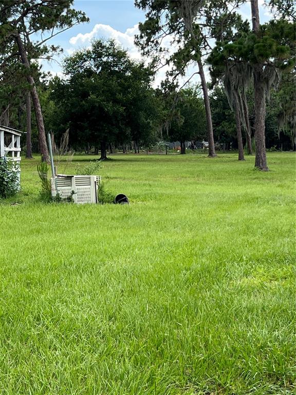 A grassy field features a discarded air conditioning unit and a small shed structure — 3760 KAISER AVENUE, ST CLOUD, FL
