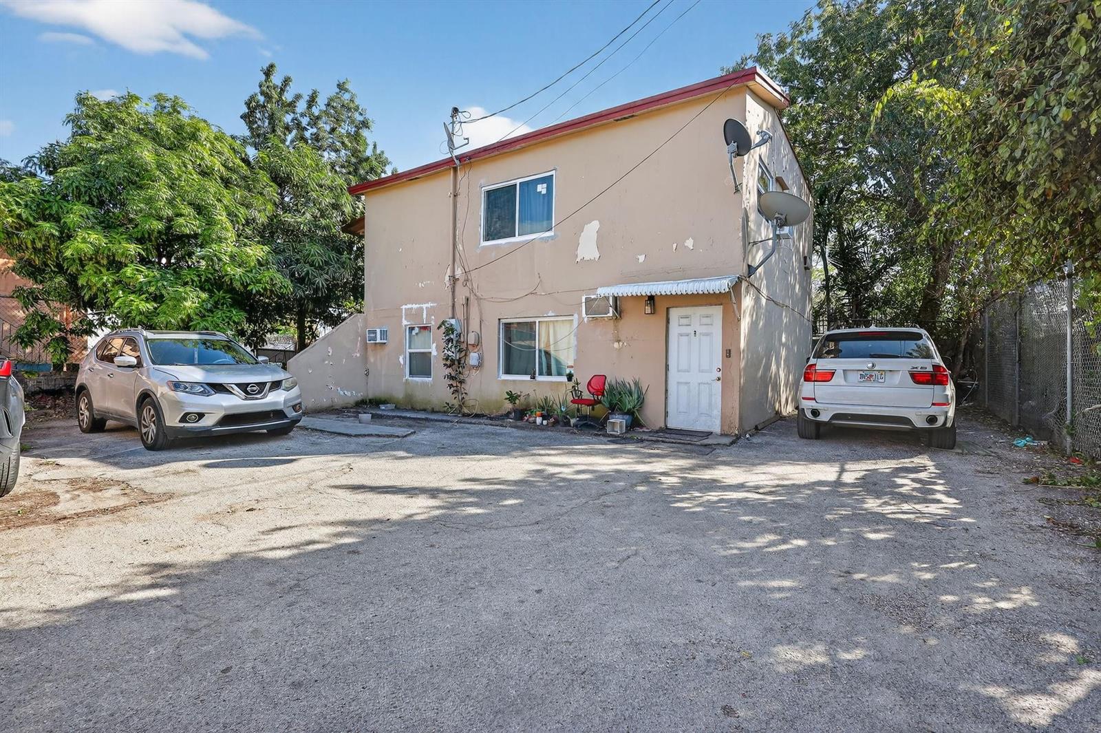 A two-story beige stucco building with two parked cars in a gravel driveway — 2168 NW 28 Street, Miami FL 33142, MIAMI, FL