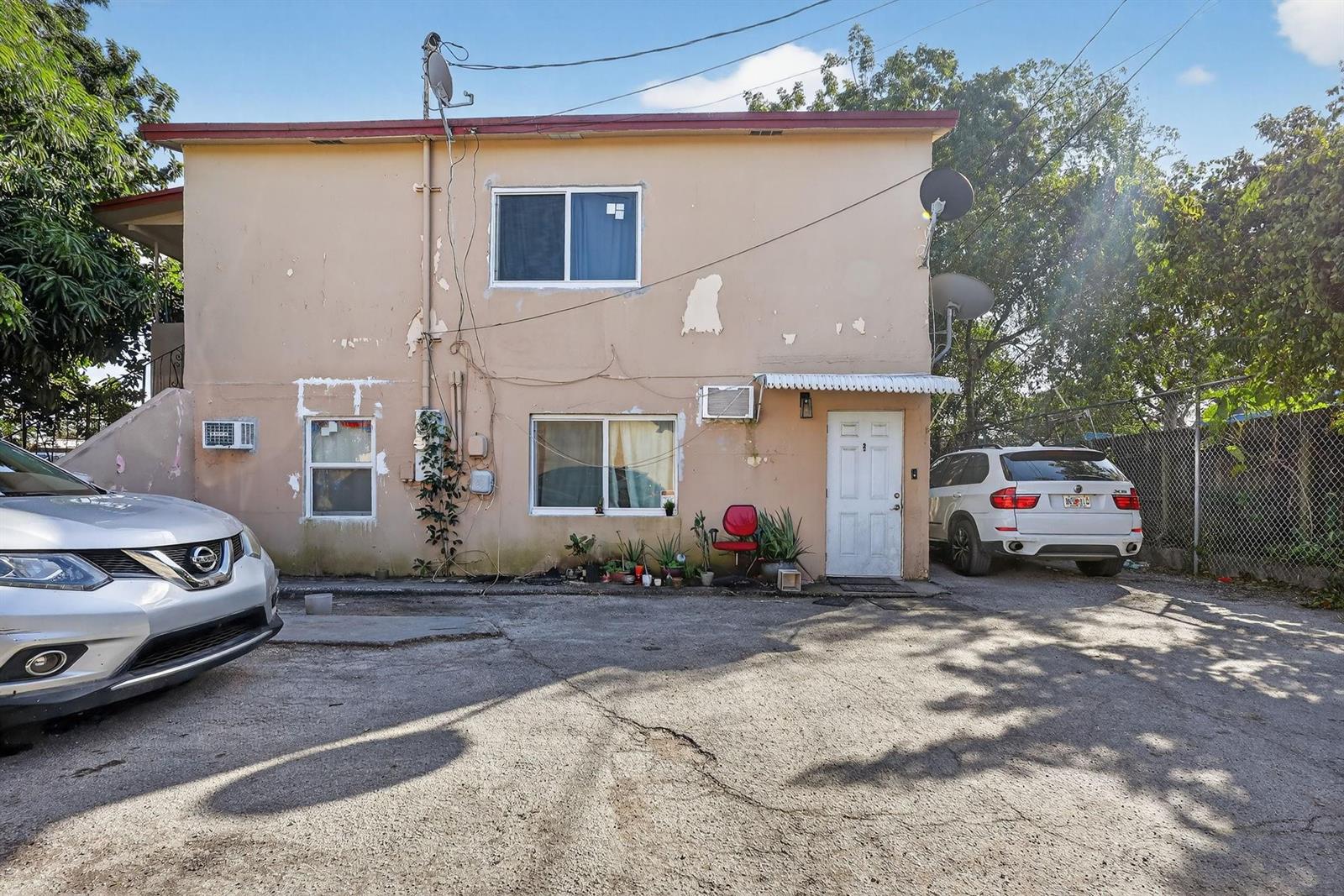 A two-story beige stucco building with peeling paint, two cars parked in front, and windows — 2168 NW 28 Street, Miami FL 33142, MIAMI, FL