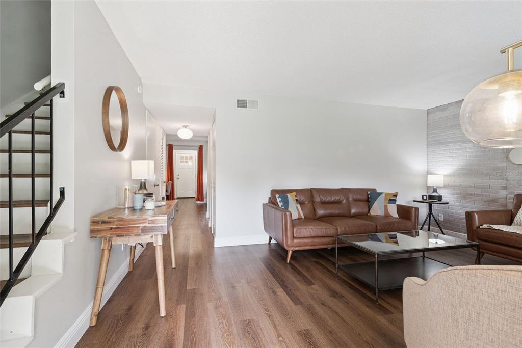 A living room features wood flooring, a brown leather sofa, and a brick accent wall — 820 PARK LAKE CIRCLE UNIT 11, MAITLAND, FL