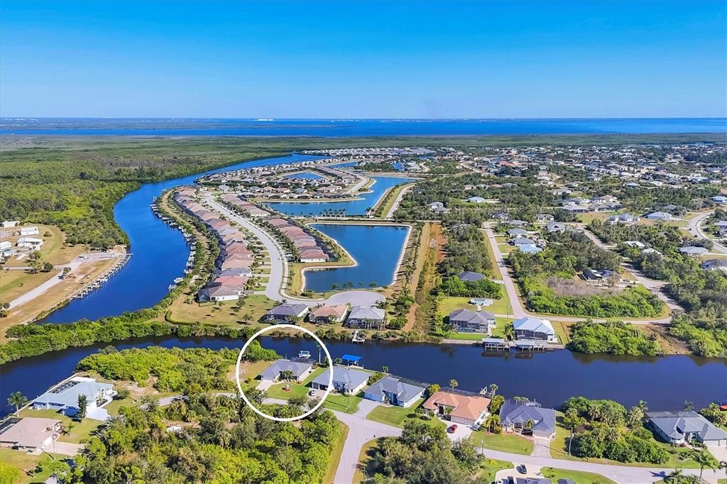 An aerial view shows a single-story house circled in a residential neighborhood near a canal — 8058 SANTA CRUZ DRIVE, PORT CHARLOTTE, FL