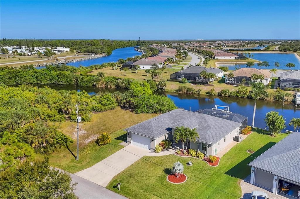 An aerial view shows a single-story house with a pool cage beside a canal — 8058 SANTA CRUZ DRIVE, PORT CHARLOTTE, FL