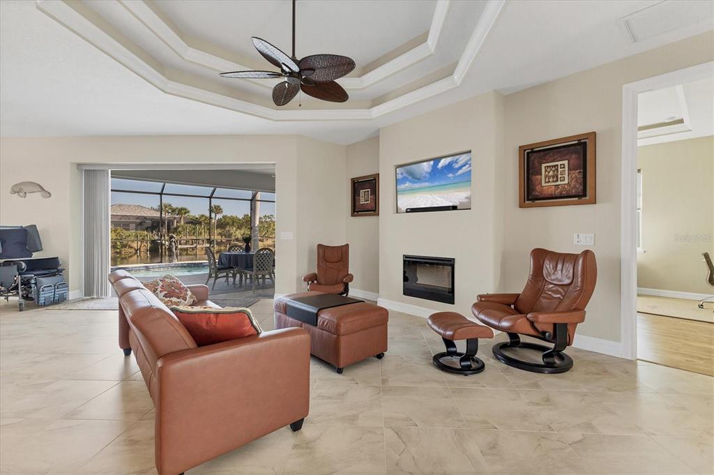 A living room with a fireplace, leather furniture, and a view of a pool area — 8058 SANTA CRUZ DRIVE, PORT CHARLOTTE, FL