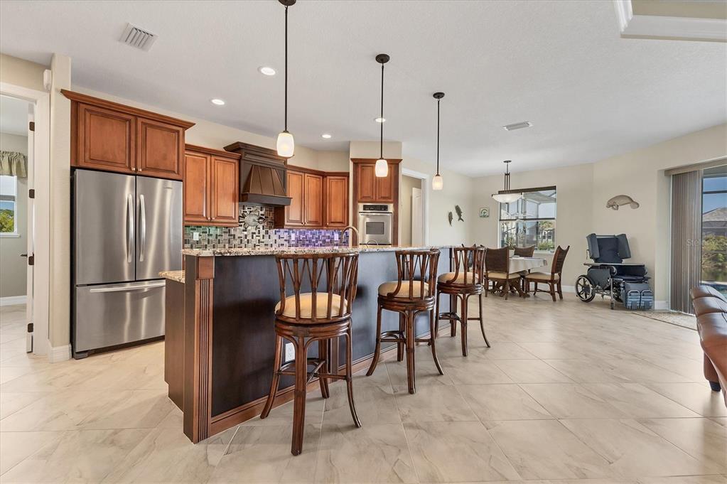 A kitchen with wood cabinets, granite countertops, and a breakfast bar with three stools — 8058 SANTA CRUZ DRIVE, PORT CHARLOTTE, FL