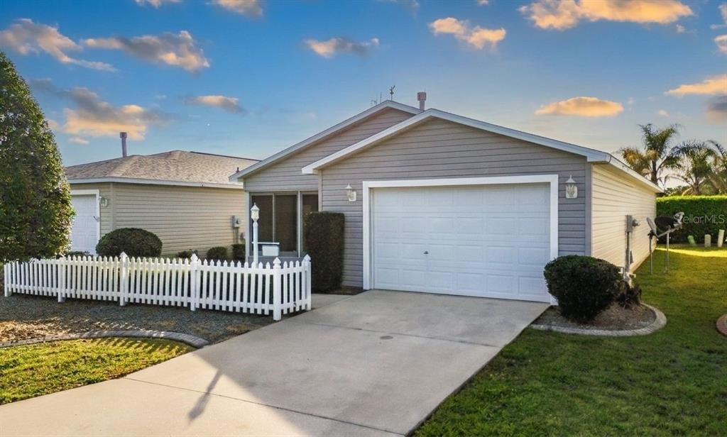 A single-story house with gray siding, a white garage door, and a white picket fence — 1626 GIBBES WAY, THE VILLAGES, FL