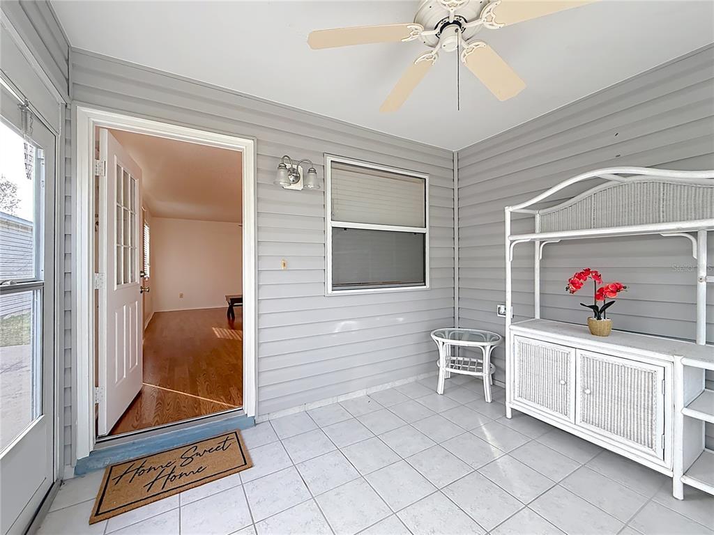 A sunroom features gray horizontal siding, white tile flooring, a ceiling fan, and a white hutch — 1626 GIBBES WAY, THE VILLAGES, FL