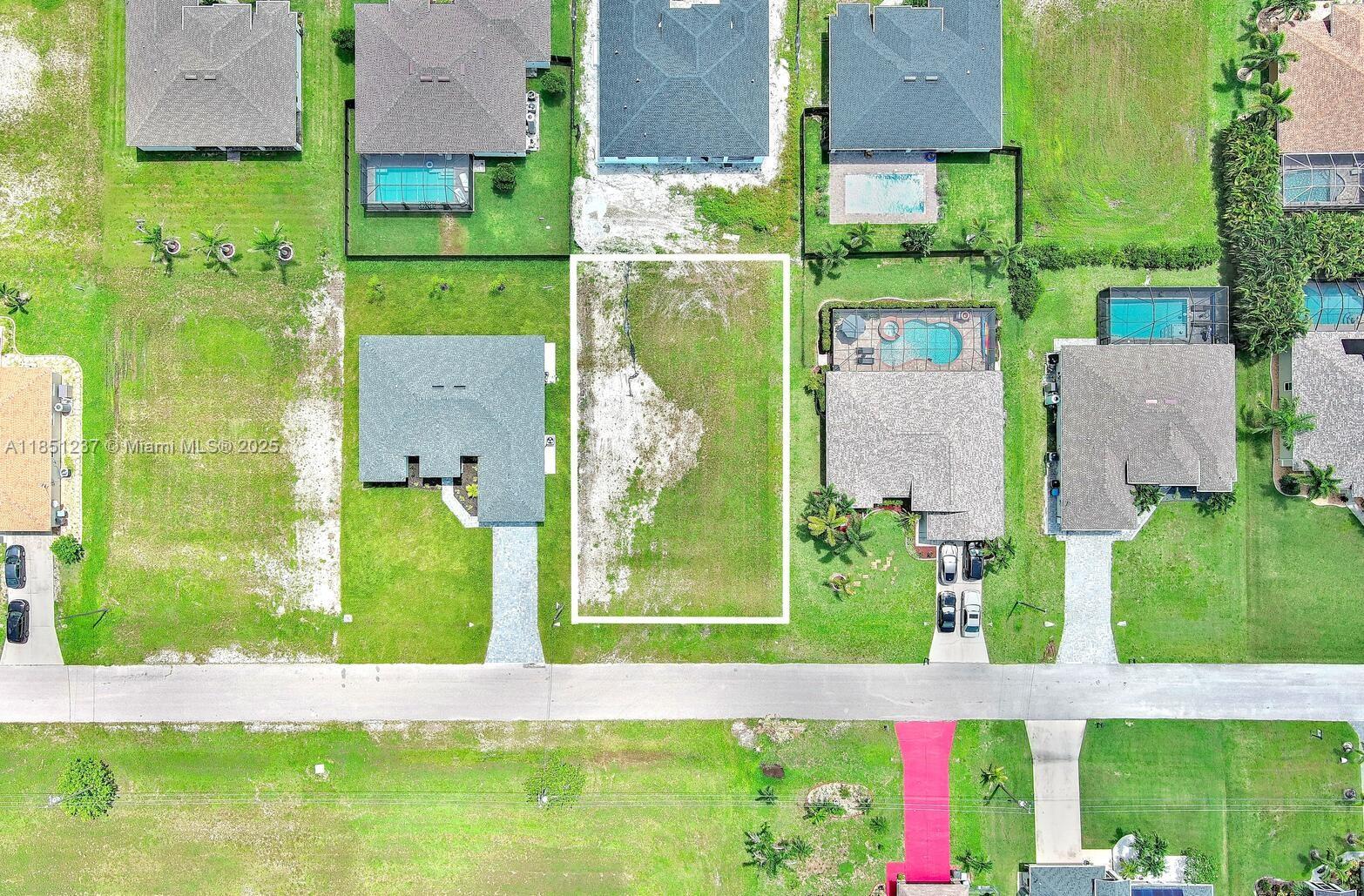 An aerial view shows a vacant residential lot situated between two houses in a neighborhood — 1025 NW 35th Place, Cape Coral FL 33993, CAPE CORAL, FL