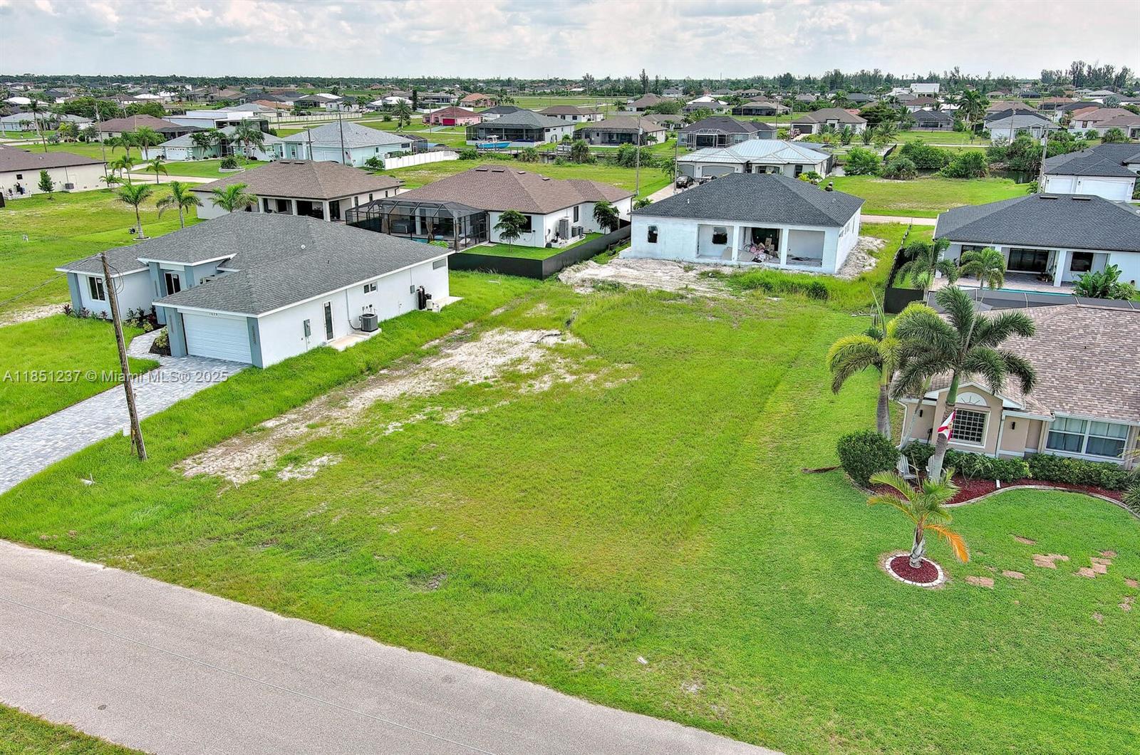 An aerial view shows a vacant residential lot situated between two single-family homes — 1025 NW 35th Place, Cape Coral FL 33993, CAPE CORAL, FL